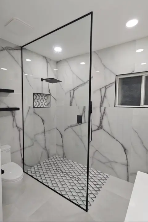 Walk-in shower with white Calacatta-look porcelain walls, matte black rain shower set and mosaic niche