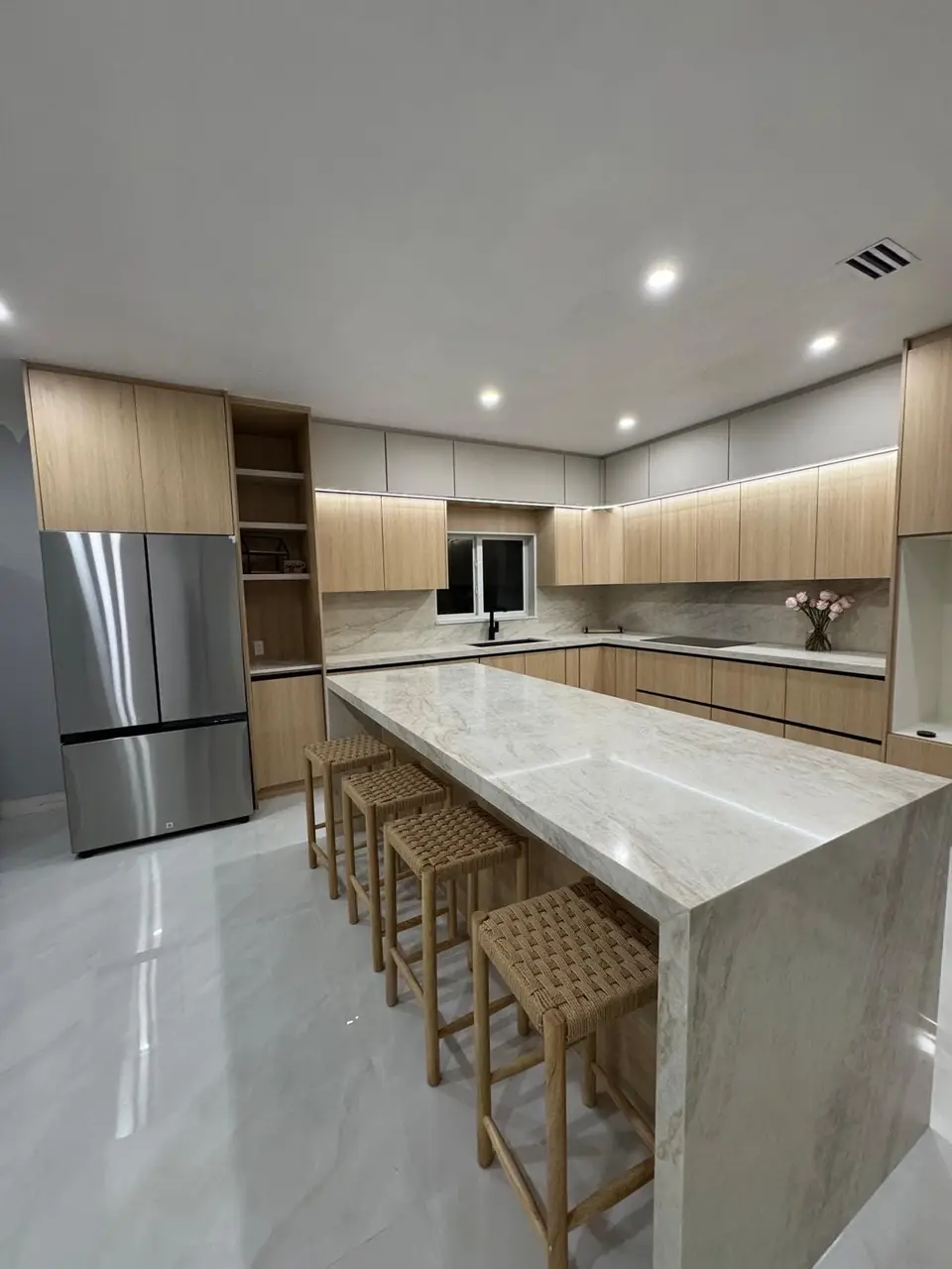 Light oak and white kitchen with marble-look waterfall island and under-cabinet lighting