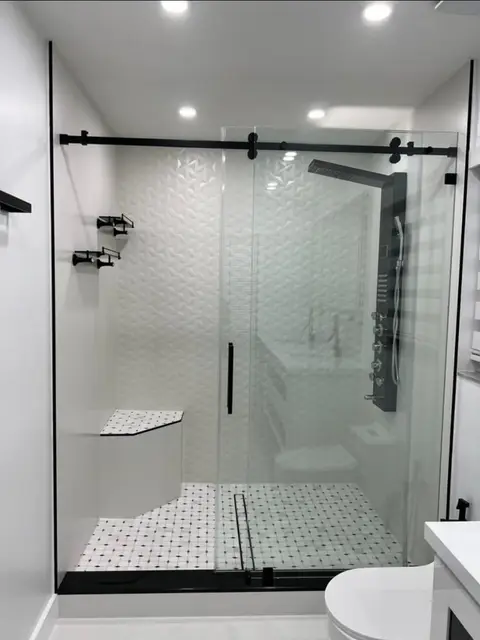 Shower with textured white tile, black sliding glass door and multi-jet shower panel
