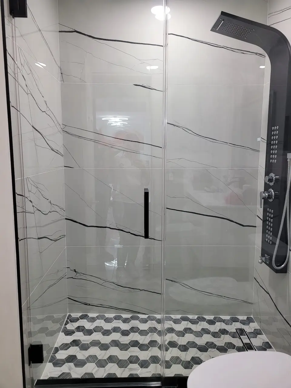 Shower in dramatic black-vein marble-look porcelain with hydromassage panel