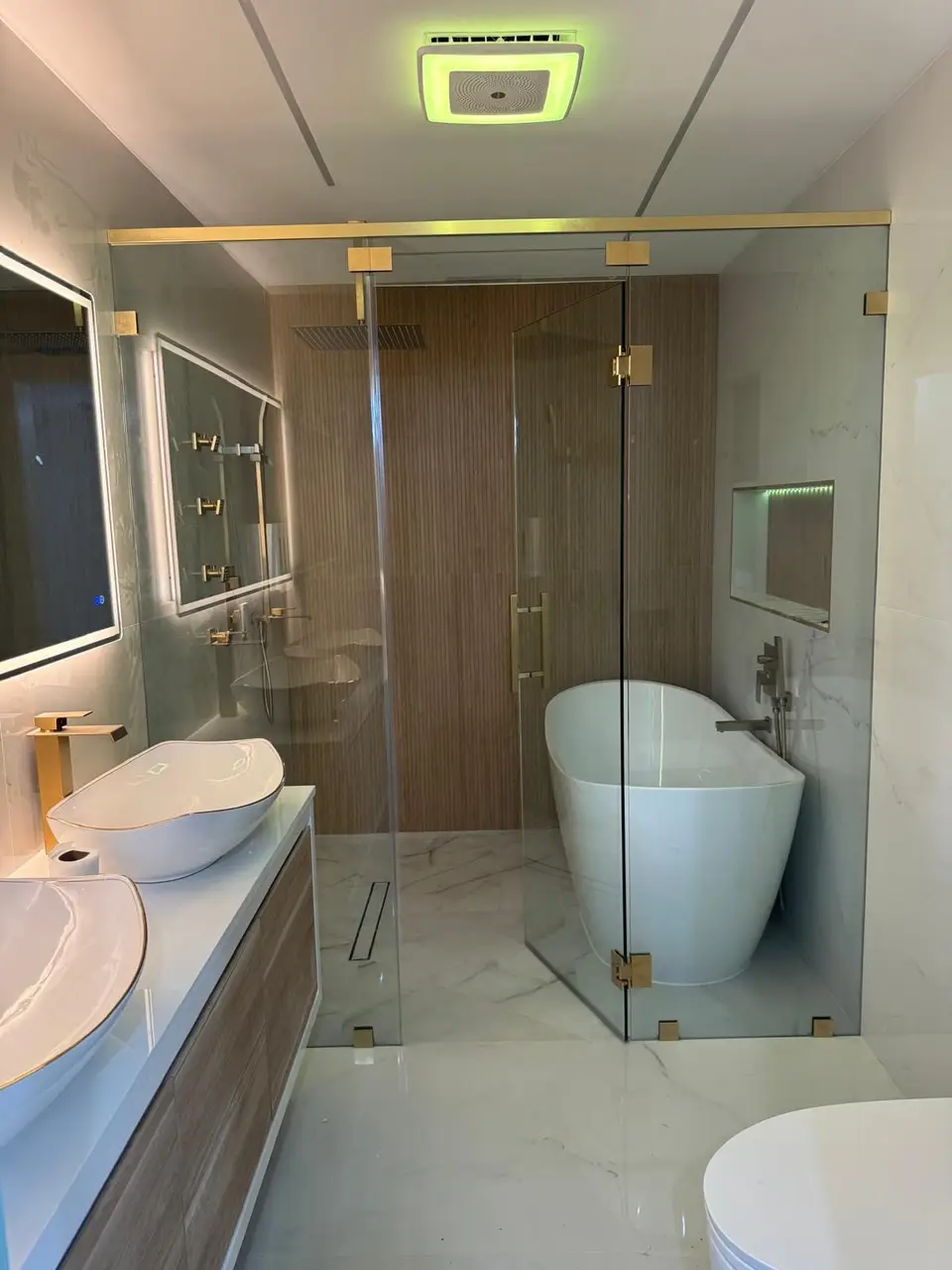 Bathroom with walnut feature wall, brass fixtures, freestanding tub and LED mirror