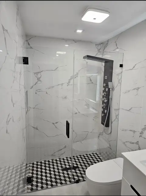 Frameless glass shower with white marble-look porcelain walls