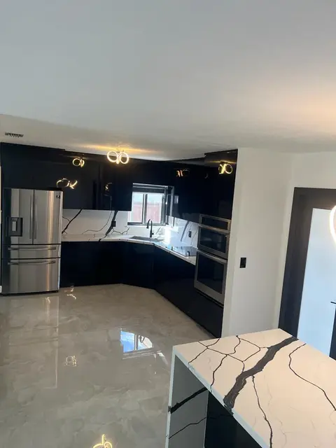 Black kitchen with marble-look island and statement chandelier