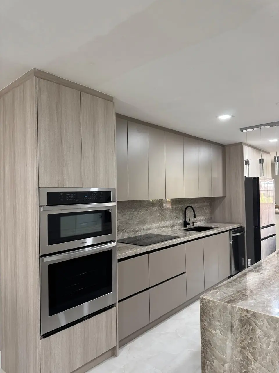 Light oak and gray kitchen with stone backsplash and built-in ovens