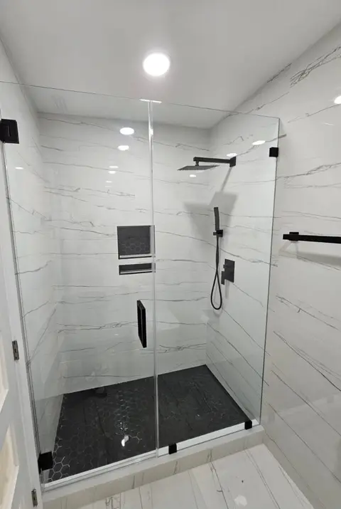 Shower with white marble-look walls, black rain head, handheld set and tiled niche